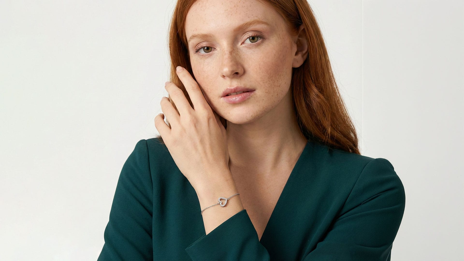 examples-images-ai-2 Long red haired woman in a dark green top, showing off a heart-shaped silver bracelet and ring, perfect for a showcase reel or AI video.