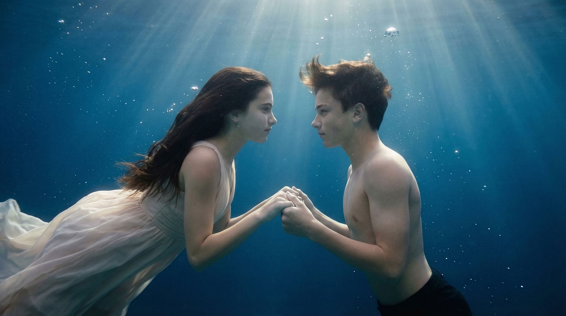 examples-images-ai-4 Two young people holding hands underwater, with the sunlight surrounding them: a cinematic moment perfect for an AI Reel or Video creation.
